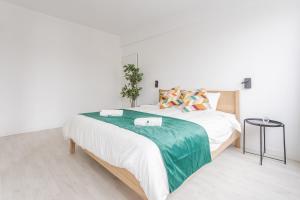 a white bedroom with a large bed with a green blanket at Center of Antwerp, Fully Equipped, Train Station in Antwerp