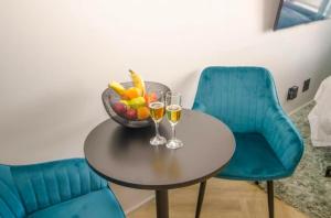 una mesa con dos copas de vino y un tazón de fruta en Executive City Micro Living in Long Street at One Thibault en Ciudad del Cabo