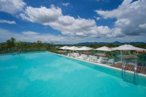 a large swimming pool with chairs and umbrellas at OceanStone 1-BR next building view in Bang Tao Beach