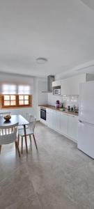 a white kitchen with a table and a white refrigerator at ESTUDIO LA ESTRELLA in Candelaria