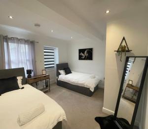 a bedroom with two beds and a mirror at WATCH CHANGING OF THE GUARD AND WALK TO THE CASTLE! 2 Bedroom Apartment in Windsor