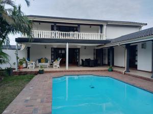 a villa with a swimming pool in front of a house at NoniSands Guesthouse in Uvongo Beach