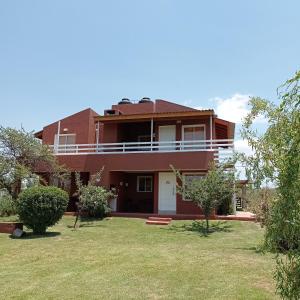 a large red house with a lawn in front of it at Cabañas Espinillos del Lago in Potrero de Garay