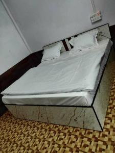 a bed in a room with white sheets and pillows at SPOT ON Hotel New Bright in Garhmuktesar