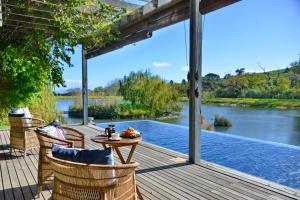a deck with chairs and a table with a view of a river at Ladybird Lodge in Stellenbosch