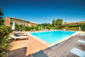 einen Pool mit Stühlen und Sonnenschirmen neben einem Gebäude in der Unterkunft Luxuryloft La Guarnigione in Valeggio sul Mincio