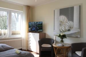 Schlafzimmer mit einem Bett, einem TV und einem Tisch in der Unterkunft Pension Landart in Wangerland