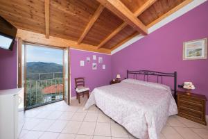 um quarto com paredes roxas, uma cama e uma janela em Agriturismo Daniela em Bracelli