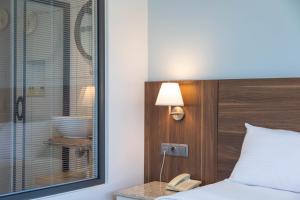 a bedroom with a bed and a window and a telephone at Bronze Hotel in Oludeniz