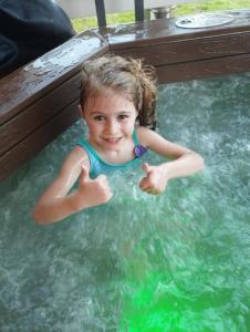 Sielanówek - Orzechowa Chatka z sauną wanną termalną jacuzzi في جيفيتس: فتاة صغيرة تعطي انطباع جيد في حمام السباحة