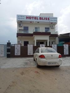 a white car parked in front of a hotel building at OYO Hotel Bliss in Rewāri