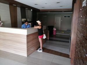 a woman standing at a counter in a hotel lobby at Condo Azur Suites A125 Amani Resorts Residences , 5 minutes Airport, Netflix, Stylish, Cozy with Luxurious Swimming Pool in Pusok