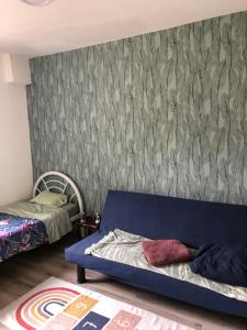 um quarto com um sofá azul em frente a uma parede em Ty case péi em Saint-Aignan