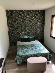 um quarto com uma cama com uma parede floral em Ty case péi em Saint-Aignan