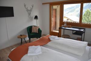 Un dormitorio con una cama y un escritorio y una ventana. en Hotel Pazzola, en Disentis