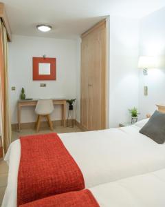 1 dormitorio con cama blanca y escritorio en Apartamentos Oasis Sol, en Maspalomas