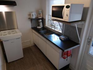 a small kitchen with a microwave and a sink at Appartement met inpandig balkon, 150 meter verwijderd van strand en centrum in Zoutelande