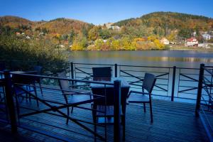 una mesa y sillas en una terraza junto a un lago en Penzión Windšachta, en Štiavnické Bane