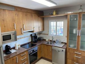 Una cocina con armarios de madera, fregadero y microondas. en Las Marinas, en Vera 7 fotos más