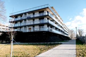 a building in front of a field with a sidewalk at Blue Baltic & SPA in Dziwnów