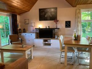 a living room with a table and a television at Het Karnhuis in Schoondijke