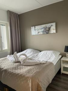 um quarto com uma cama com lençóis brancos e uma fotografia na parede em Spa Hotel RED em Tahkovuori