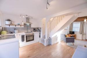 a kitchen with white cabinets and a staircase in a room at Button Cottage in Wickham Market