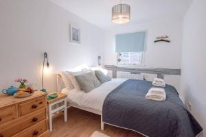 a bedroom with a large bed and a wooden dresser at Button Cottage in Wickham Market