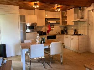 a kitchen with a wooden table and white chairs at Het Karnhuis in Schoondijke