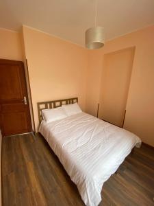 um quarto com uma cama branca e piso em madeira em Appartements touristique - La Colombière em Lourdes