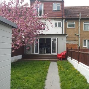 a yard with a red chair in front of a house at Family home with easy commute to London! in Croydon