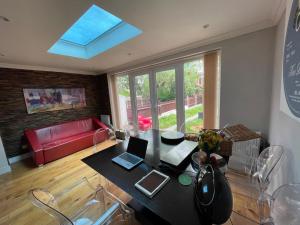 een woonkamer met een tafel met twee laptops erop bij Family home with easy commute to London! in Croydon