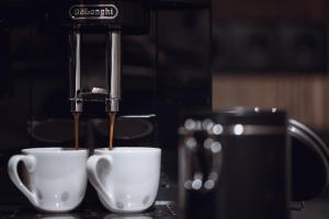 a coffee machine pouring coffee into two white cups at Amus Suites Dolomites in Anterselva di Mezzo