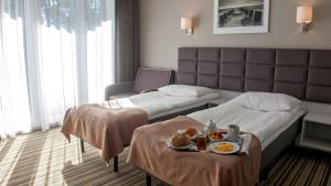 a hotel room with two beds and a tray of food at Waterside Resort in Darlowko