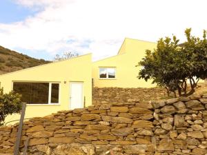 una casa amarilla detrás de una pared de piedra en EiraDouro Casa Amendoeira, 