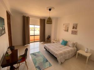 a bedroom with a bed and a table and a window at Casa Luana - Rooms in Sagres