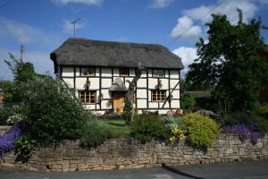 an old white cottage with a thatched roof at The Cobblers Bed and Breakfast in Bishampton