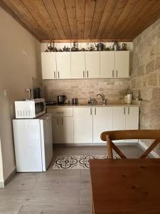 cocina con armarios blancos y nevera blanca en צימר חצר שמואלי - יחידת אירוח זוגית במושב אילניה en Ilaniyya