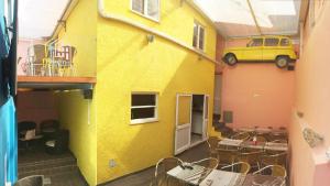 a yellow building with tables and a car on it at Meeting Hostel in Figueira da Foz