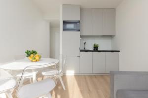 a white kitchen with a white table and chairs at Cosy Dream City Center Apartment by Renters in Warsaw