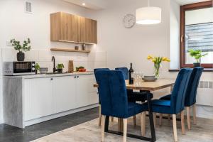 a kitchen with a wooden table and blue chairs at udanypobyt Apartamenty Przy Dolinach C i D in Kościelisko