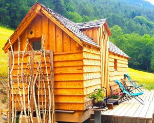 een houten hut met een terras en een stoel bij LE NOYER DU BARON in Le Lauzet-Ubaye