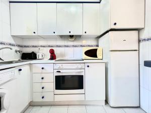 a white kitchen with white cabinets and appliances at Bungalow Los Balcones in Torrevieja