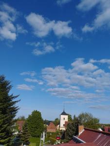 a white church with a steeple and a blue sky at Zum alten Schmied Vermietung und Verpachtung Schönfeld 