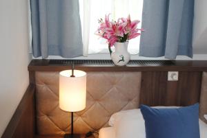 Un dormitorio con una ventana con un jarrón de flores en una cama en Salzburg Hotel Lilienhof, en Salzburgo