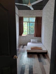 a bedroom with a bed in a room with a window at Basung Homestay Sinsuran in Kota Kinabalu