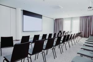 Sala de conferencias con sillas y pantalla de proyección en Hotel Das Grambacher 