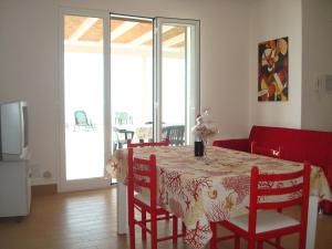 a dining room with a table with red chairs and a room with a balcony at Mare d'Amuri in Porto Empedocle