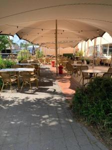 a patio with tables and chairs under an umbrella at Chalet Uppsala, Plus Sauna in Gramsbergen