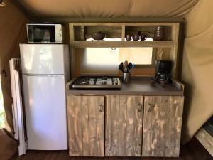 a small kitchen with a refrigerator and a stove at Camping Le Mondou in Saint-Julien-de-Lampon
